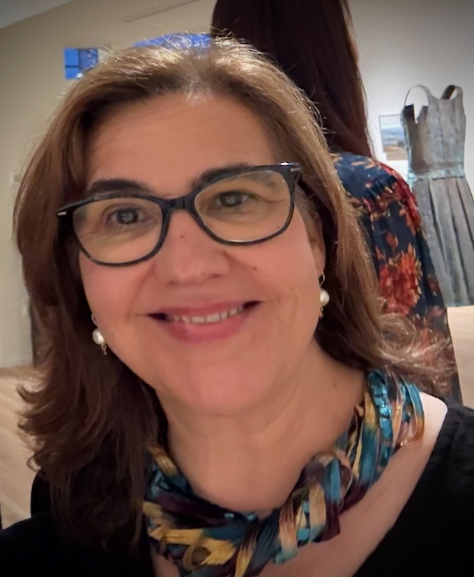 Christine Lafuente, painting, drawing, and printmaking instructor at A Maker's Circle art studio in Pottersville NJ, smiling in front of artwork