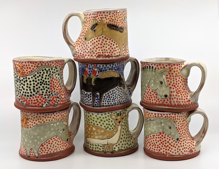 Hand-built ceramic mugs decorated with painted animals and colorful dotted patterns, made by pottery instructor Laurie Scupp at A Maker's Circle